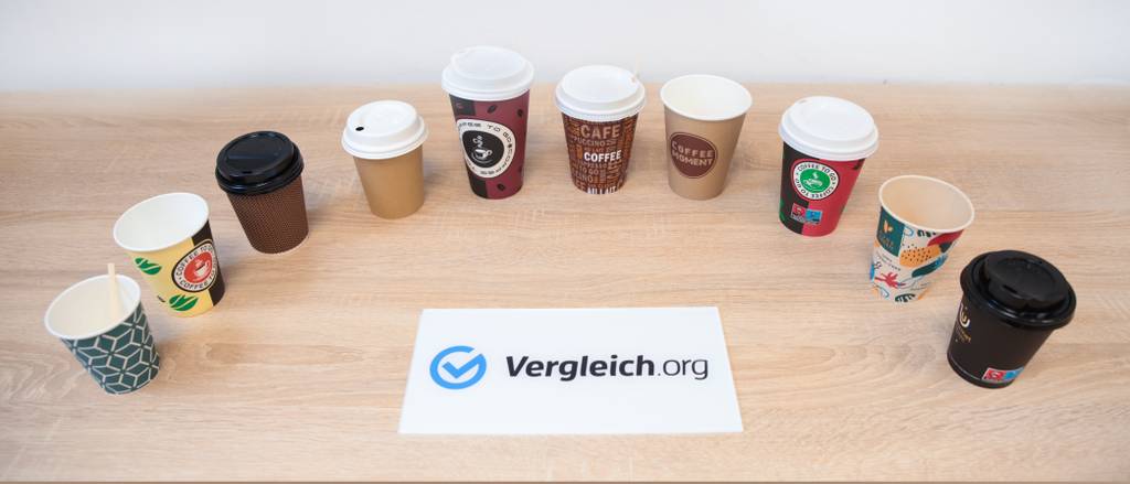 Coffee-To-Go-Becher-Pappe-Test: Alle Einwegbecher sind hinter dem Schild von Vergleich.org zu sehen.