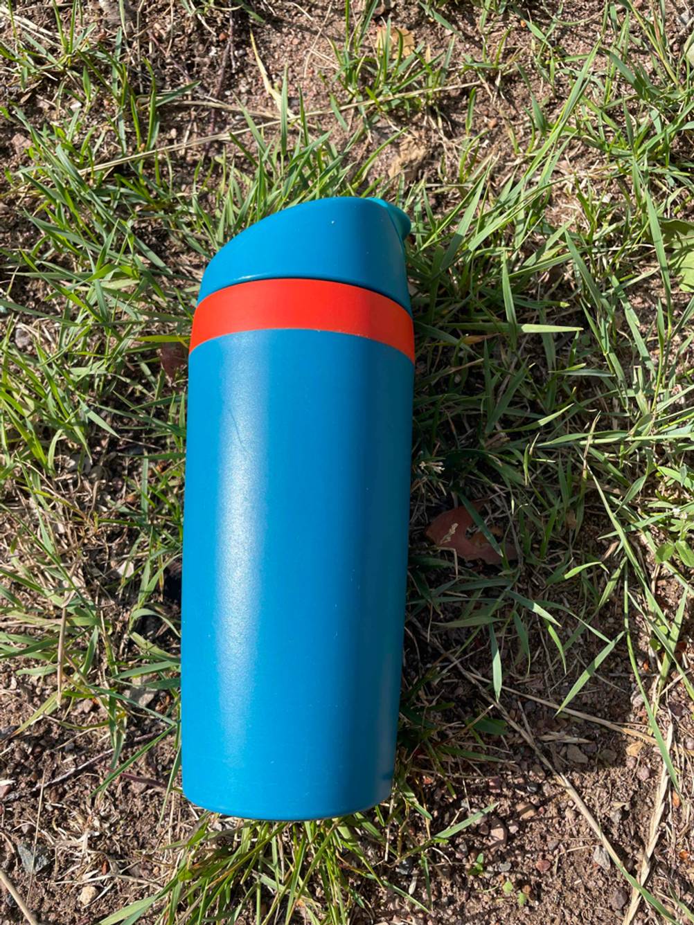 Ein getesteter Coffee-to-go-Becher in einer Wiese.