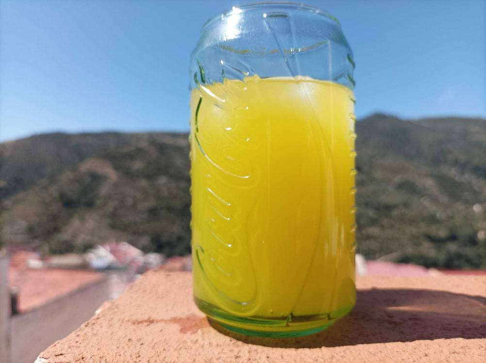 Ein getestetes Cola-Glas mit gelbem Inhalt auf einer Mauer.
