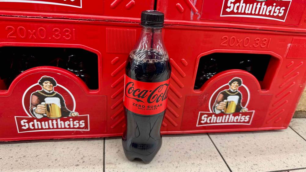 Getestet: Eine Cola ohne Zucker vor Getränkekästen auf dem Boden.