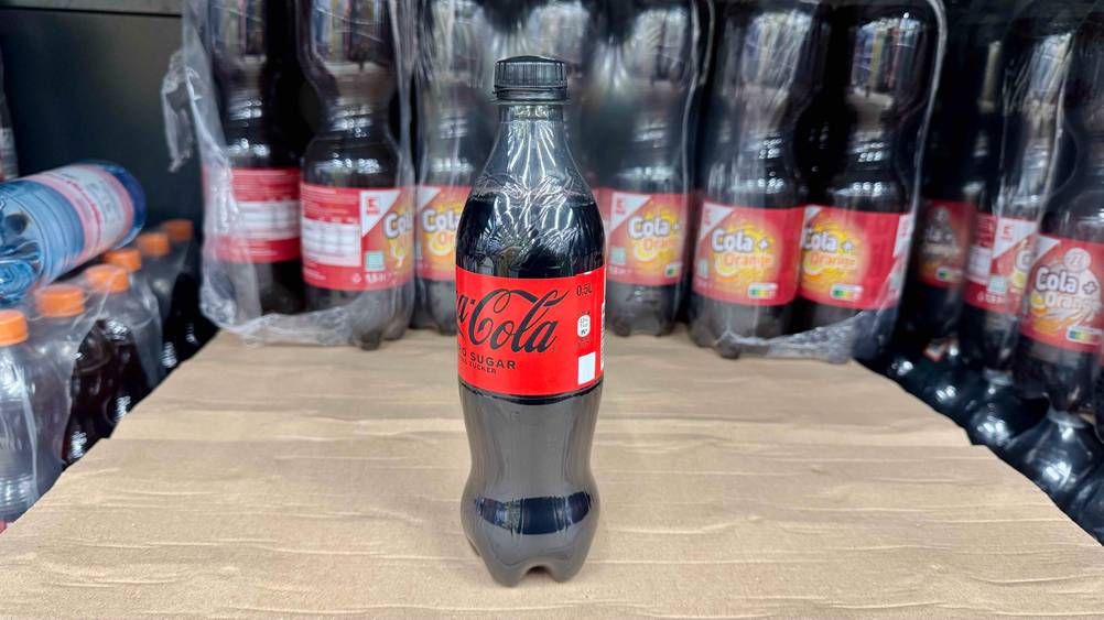 Eine Flasche der getesteten Cola ohne Zucker auf einem Karton vor mehreren anderen Flaschen.
