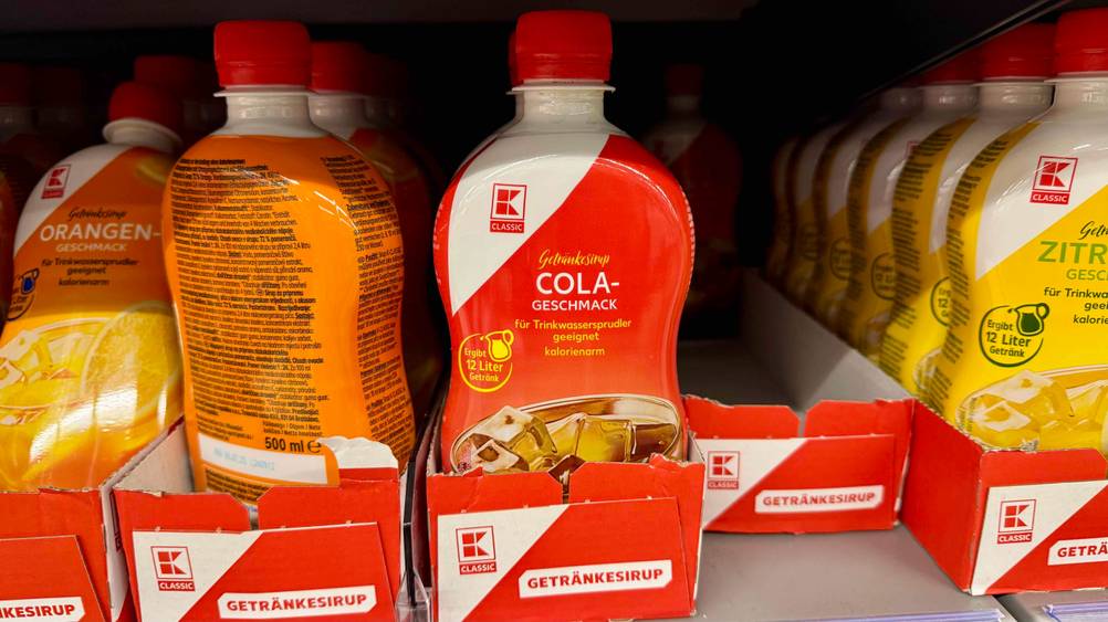 In einem Verkaufsregal stehen mehrere Flaschen des Cola-Sirups im Test.