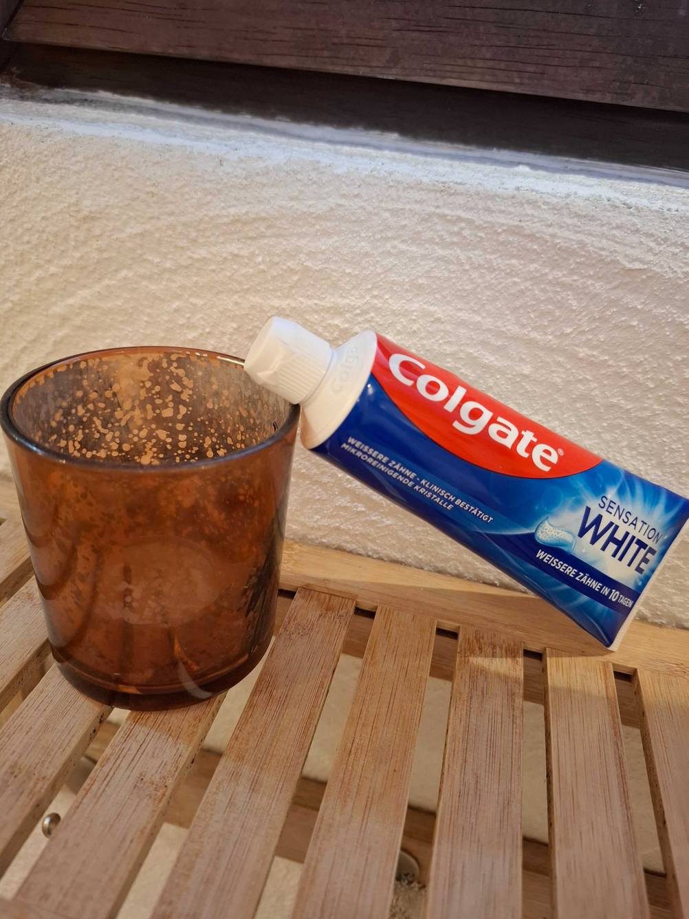 Eine Tube Whitening-Creme liegt zum testen mit der Kappe auf einem Becher.