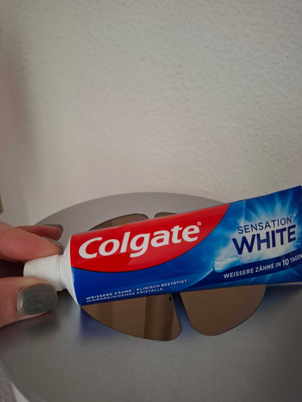 Finger öffnen die Verschlusskappe einer Tube getestete Whitening-Creme.