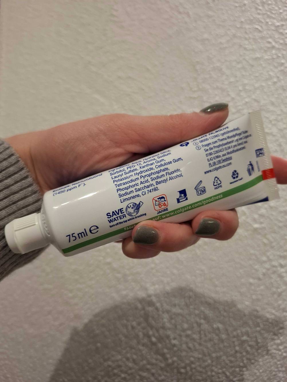 Eine Hand hält eine Tube getestete Whitening-Creme mit der Rückseite nach vorn.