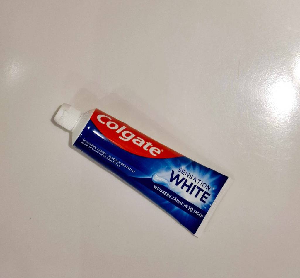 Eine Tube Whitening-Creme liegt zum testen auf einer weißen Fläche.