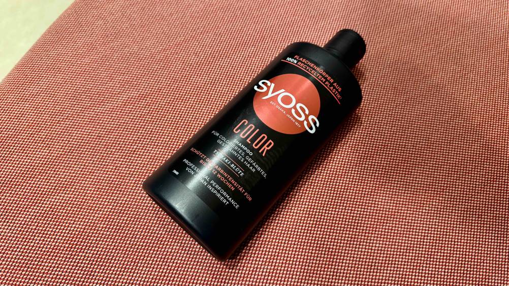 Auf einem roten Teppich liegt eine Flasche des getesteten Color-Shampoos.