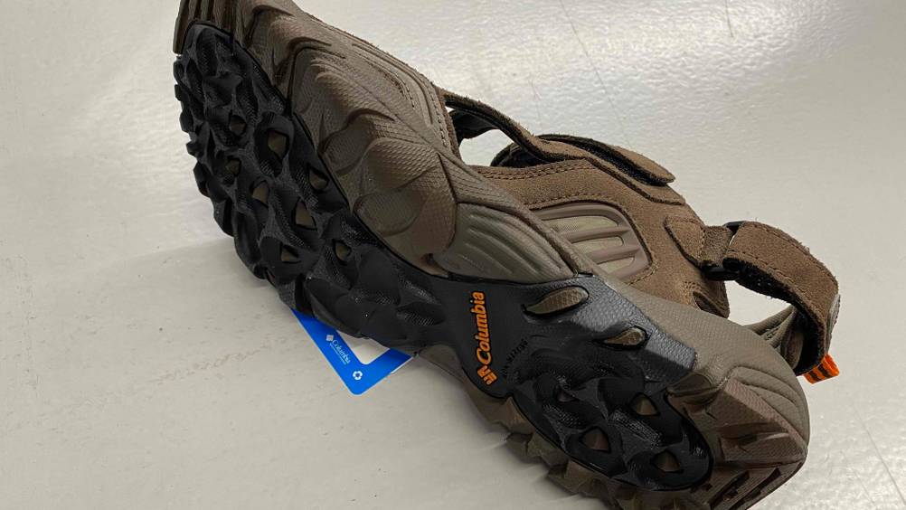 Im Test: Eine Columbia Trekkingsandale für Herrenliegt mit Sohle nach vorn auf weißer Fläche.