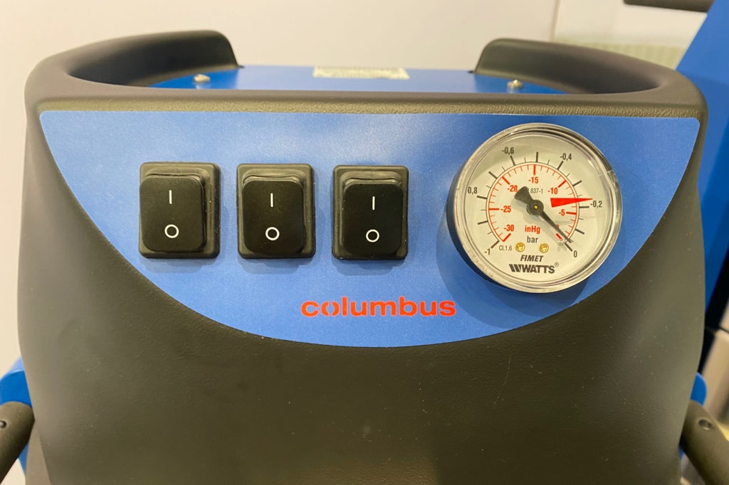 Ein- und Ausschalte-Tasten sowie Manometer auf blauem Paneel im Bereich des Deckels eines getesteten Industriestaubsaugers von Columbus.