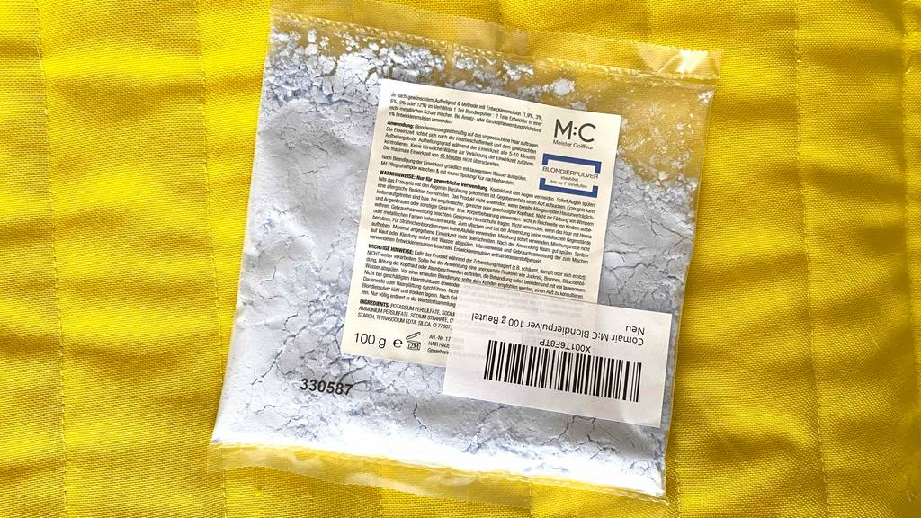 Blondierpulver im Test befindet sich in einer transparenten 100-g-Kunststofftüte auf einem gelben Untergrund.