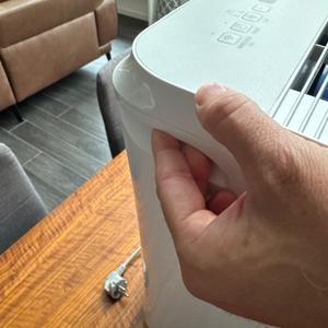 Zwei Finger liegen in einer Vertiefung zum Tragen des Comfee MDDF-20DEN7-WF