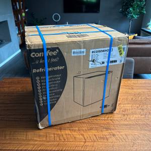Der Karton des Comfee-RCD50WH2(E)-Mini-Kühlschranks steht auf einem Tisch.