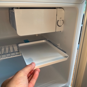 Eine Hand legt eine Plastikschale unter das Tiefkühlfach des Comfee-RCD50WH2(E)-Mini-Kühlschranks.