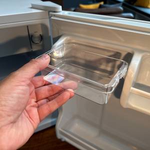 Eine Hand setzt eine Plastikbox in die Tür des Comfee-RCD50WH2(E)-Mini-Kühlschranks.