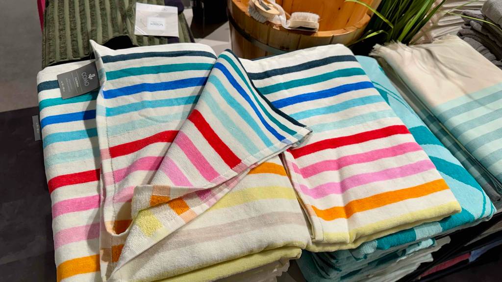 Getestet: Ein Strandtuch im bunt gestreiften Design liegt auf einem Stapel Handtücher.