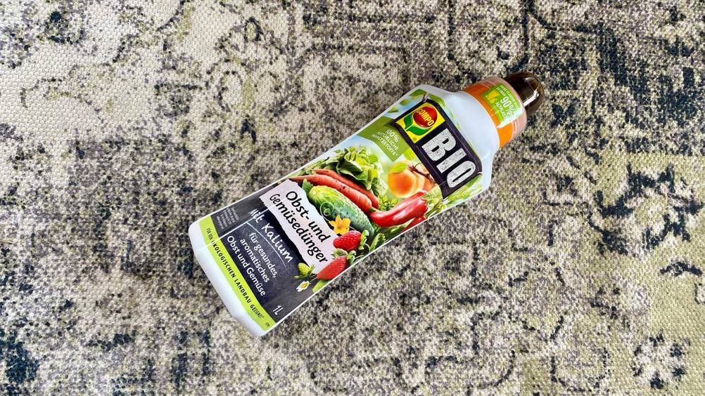 Obstbaum-Dünger-Test: Eine Flasche liegt quer auf einem Teppich.
