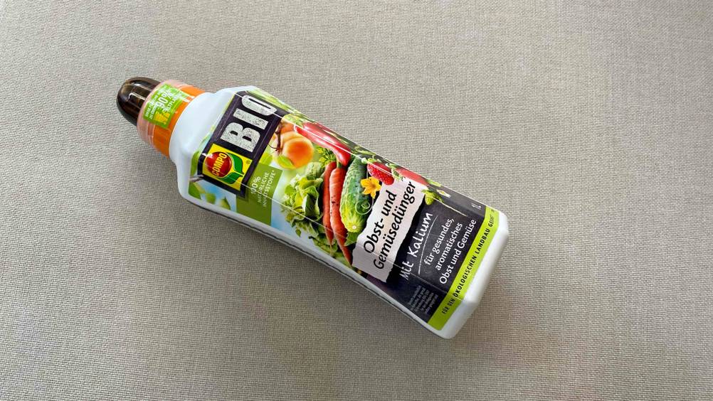 Obstbaum-Dünger-Test: Eine Flasche liegt horizontal auf einem hellen Stoff.