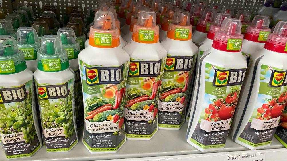 Mehrere Flaschen des getesteten Obstbaum-Dünger stehen nebeneinander in einem Verkaufsregal neben anderen Produkten.