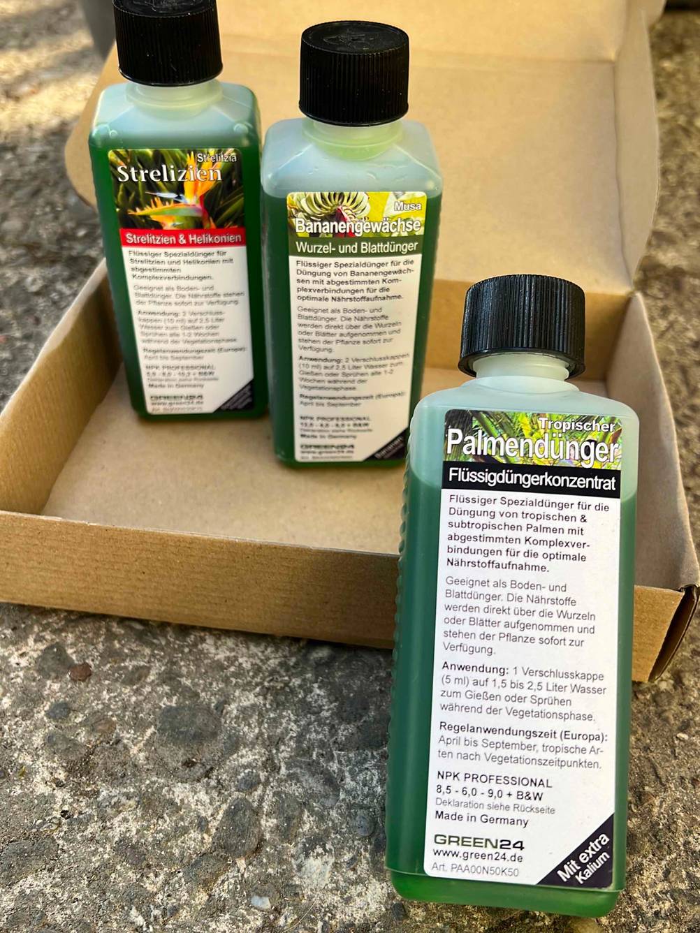 Eine Flasche Palmendünger steht zum testen vor einem Karton mit anderen Düngern.