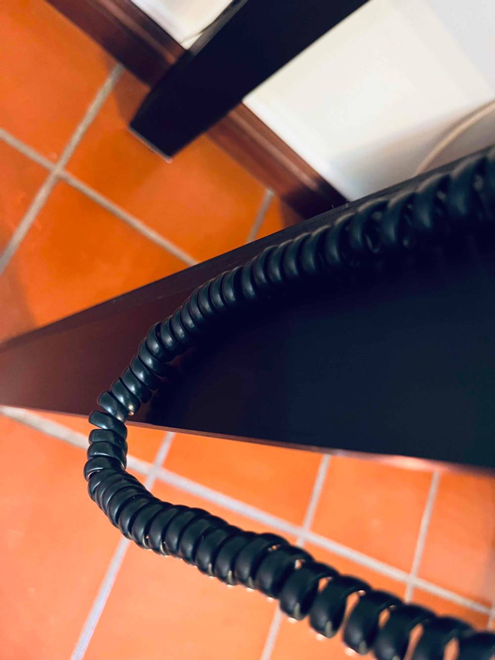 Blick von oben auf das herunterhängende Spiralkabel eines getesteten Seniorentelefons.