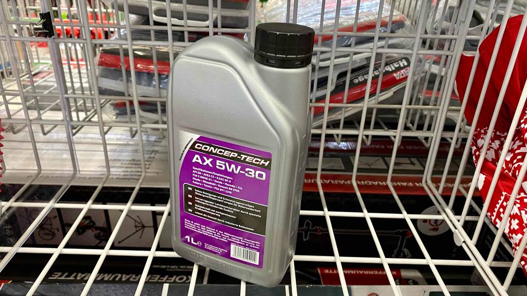 5W-30-Motoröl-Test: ein hellgraues Kunststoffgebinde mit violettfarbenem Etikett der Marke CONCEP-TECH steht in einem weißen Verkaufskorb.