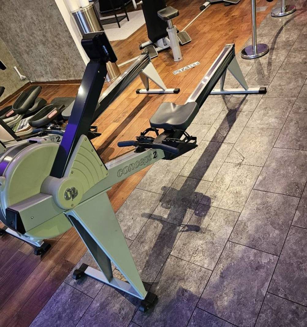 Rudergerät im Test: ein hellgrünes Modell von Concept2 steht aufgebaut neben anderen Sportgeräten in einem Trainingsraum.