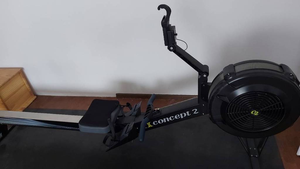 Ein schwarzes Rudergerät von Concept2 befindet sich auf einer dunklen Sportmatte.
