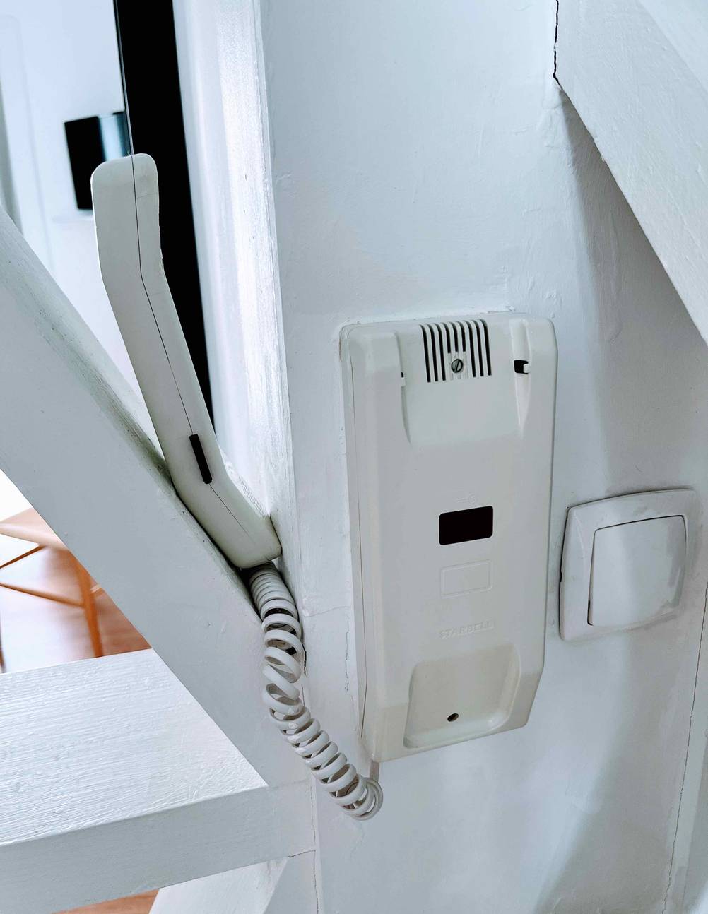 Der Hörer einer getesteten Türsprechanlage klemmt in einem schrägen Balken.