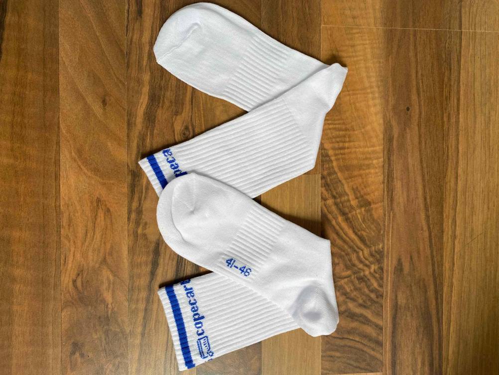 Getestete Tennissocken in Weiß liegen auf einem Holzboden.