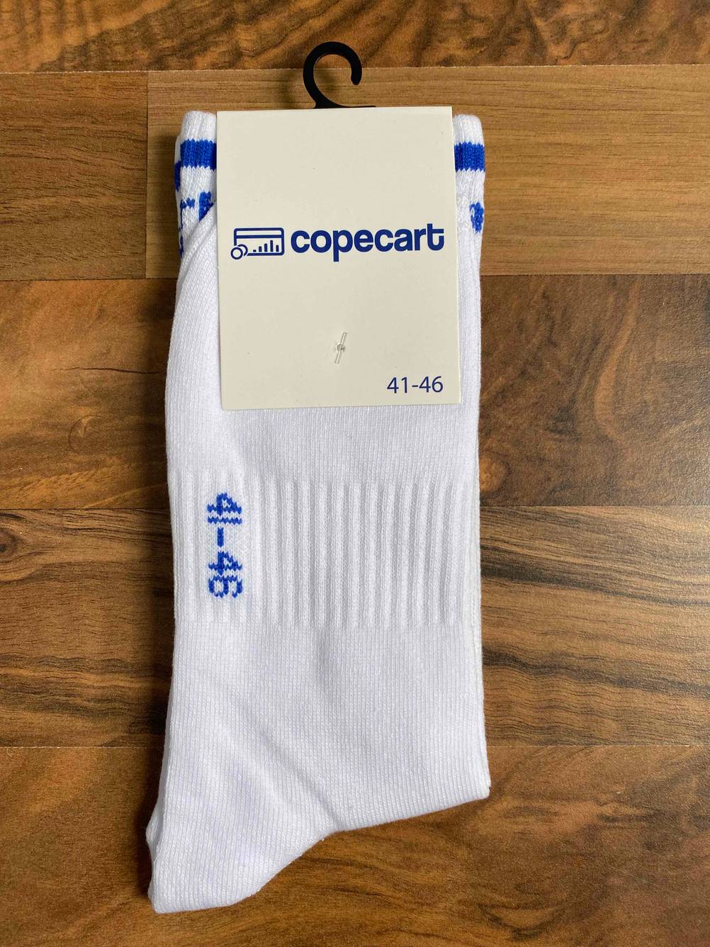 Ein Paar getestete Tennissocken in Originalverpackung auf einer Holzfläche.