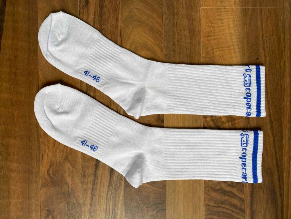 Getestete Tennissocken in Weiß liegen nebeneinander ausgebreitet auf einem Holzboden.