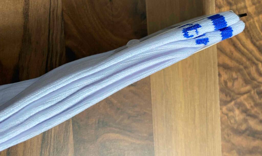 Weiße blau gestreifte Herrensocken im Test liegen zusammengefaltet auf einer Holzfläche.