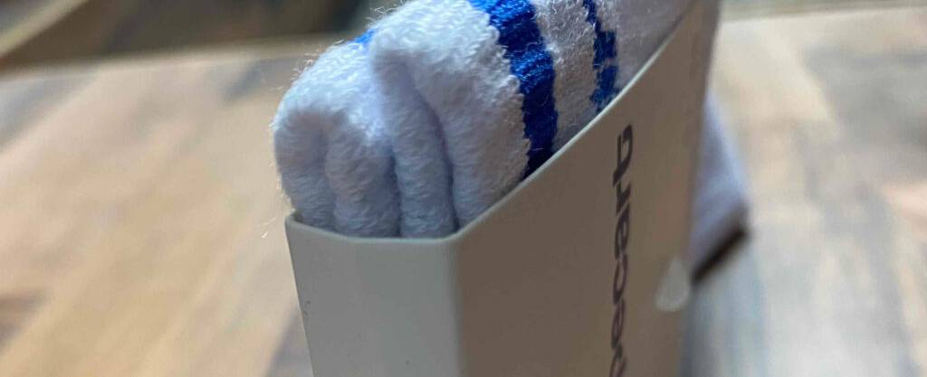 Eine Nahaufnahme von flauschigen Herrensocken im Test, die sich in Karton eingepackt auf einer Holzoberfläche befinden.