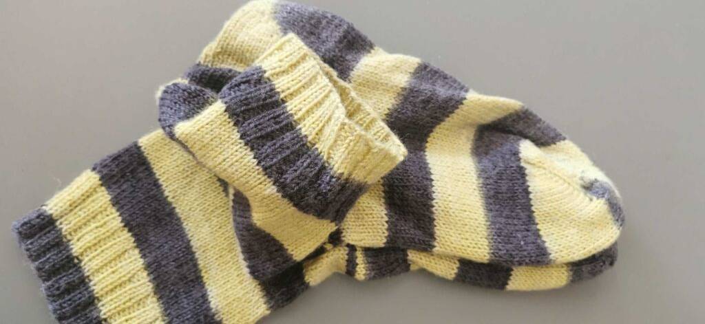 Gestreifte Herrensocken im Test liegen ausgebreitet übereinander auf einer grauen Oberfläche.