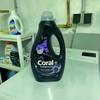 Waschmittel für schwarze Wäsche von Coral steht auf einer Waschmaschine.