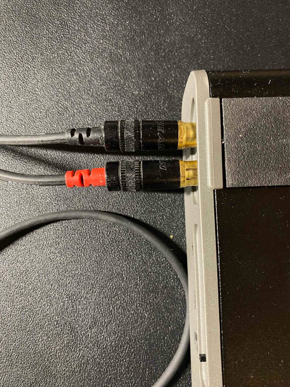 Cinch-Kabel getestet: Ein in ein Gerät eingestecktes Kabel von oben auf einer dunklen Fläche.