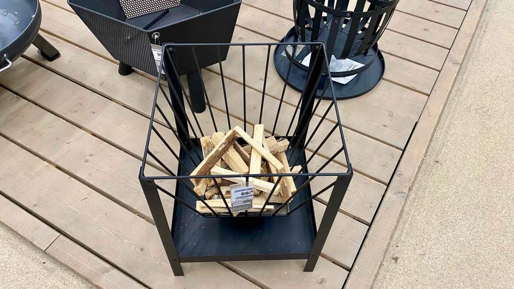 Eine getestete Feuerschale von schräg oben mit Preisschild auf einer Holzterrasse im Hintergrund andere Produkte.