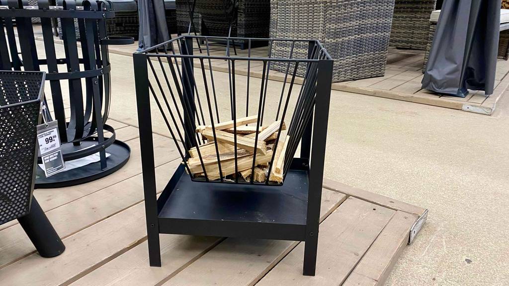 In einem Verkaufsbereich stehen vor Gartenmöbeln schwarze Feuerschalen im Test: ein viereckiges Corvo Modell inklusive Holzstückchen befindet sich im Vordergrund.