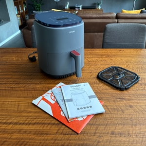 Der Lieferumfang der Cosori CAF-LI401S steht auf einem Tisch.