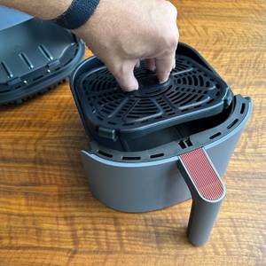 Eine Hand nimmt einen Einsatz aus dem Behälter der Cosori CAF-LI401S.