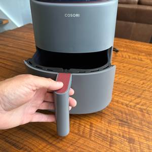 Eine Hand zieht den Behälter aus der Cosori CAF-LI401S.