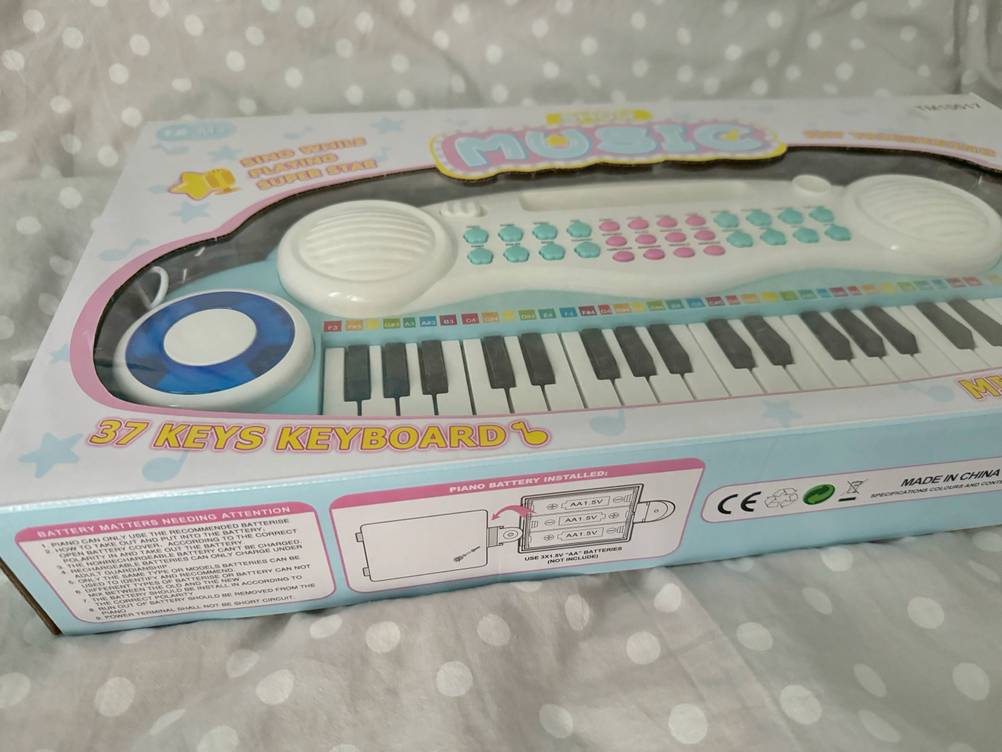Im Test: Ein originalverpacktes Kinderkeyboard von schräg seitlich auf einer weiß gepunkteten Oberfläche.