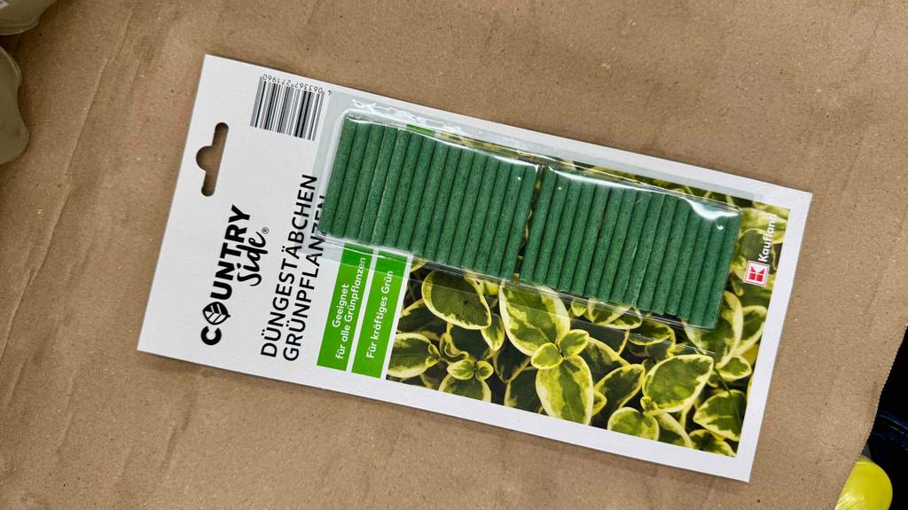 Eine Packung mit grünen Düngestäbchen im Test liegt auf einem Karton.