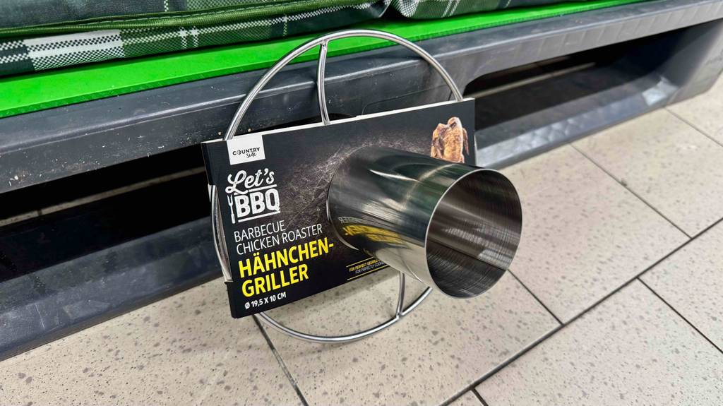 Getestet: Ein Hähnchengriller aus Edelstahl innerhalb seines Kartons lehnt an einem Verkaufsregal.