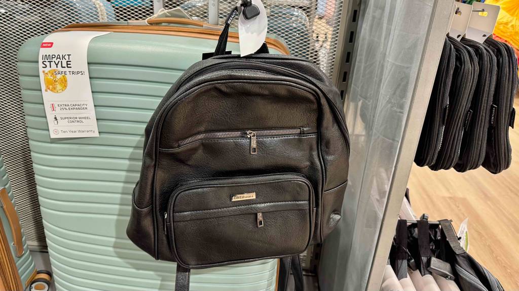 Ein Lederrucksack hängt zum testen vor einem Reisekoffer.