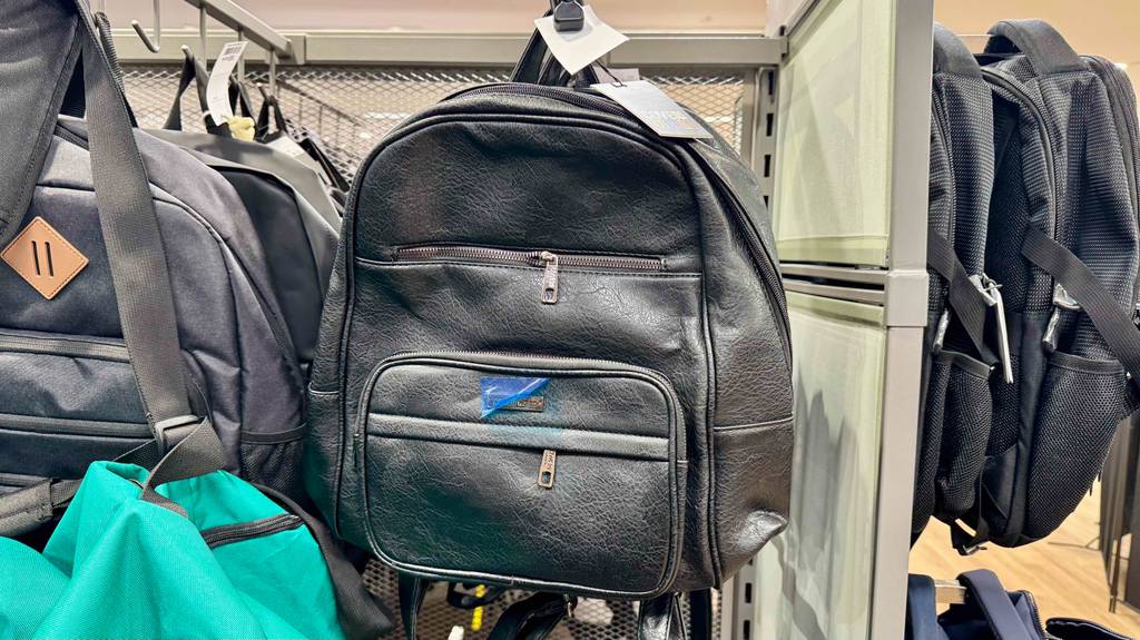 Lederrucksack im Test: Mehrere Rucksäcke hängen zwischen anderen Produkten in einem Hängeregal.