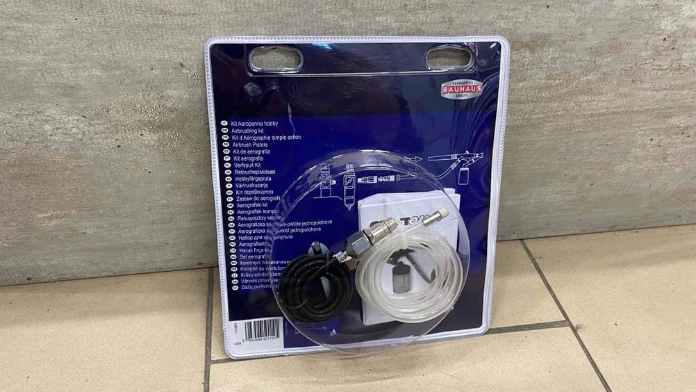 Airbrushpistole getestet: Die verpackten Schläuche lehnen an einer Betonwand.