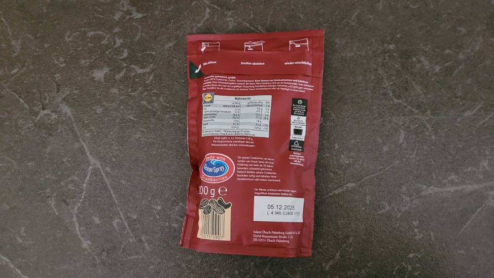 Eine Packung der getesteten Cranberries getrocknet liegt mit der Rückseite nach oben auf einer grauen. Fläche.