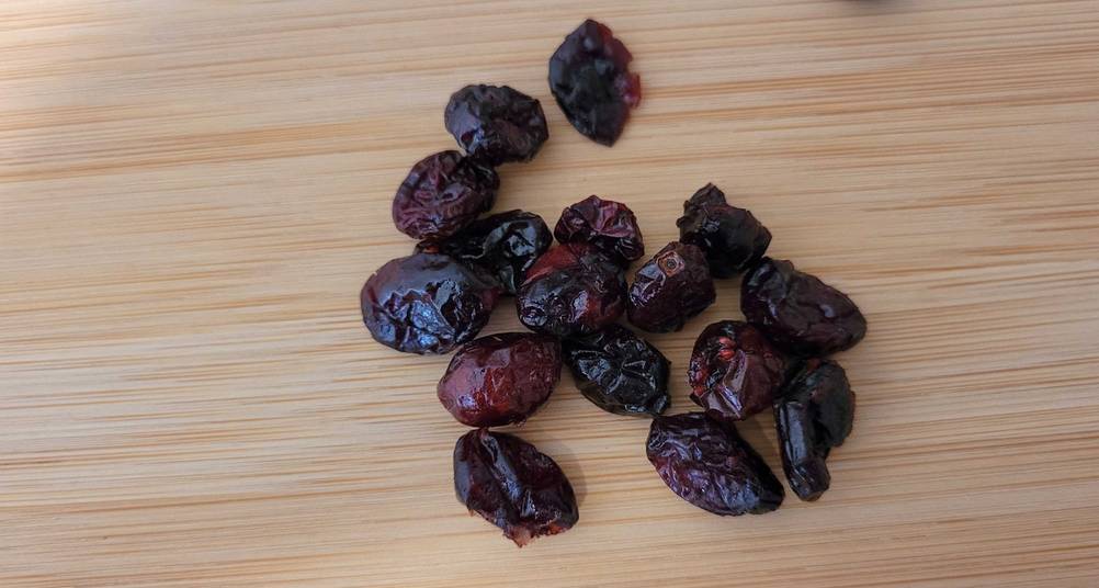 Mehrere Cranberries getrocknet im Test liegen auf einer Holzfläche.