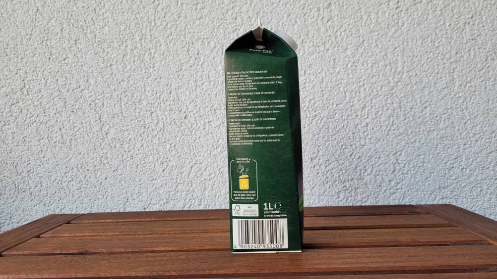 Seitenansicht einer Packung des getesteten Cranberrysaftes auf einem Holztisch.